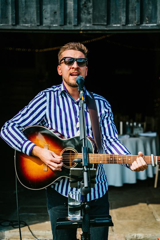 Tom Ryder singing and playing acoustic guitar in a barn at a wedding